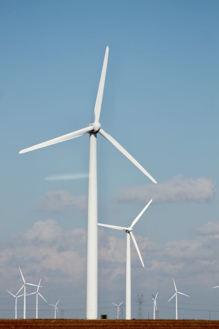 A series of tall wind turbines generating renewable energy in a clear open field.