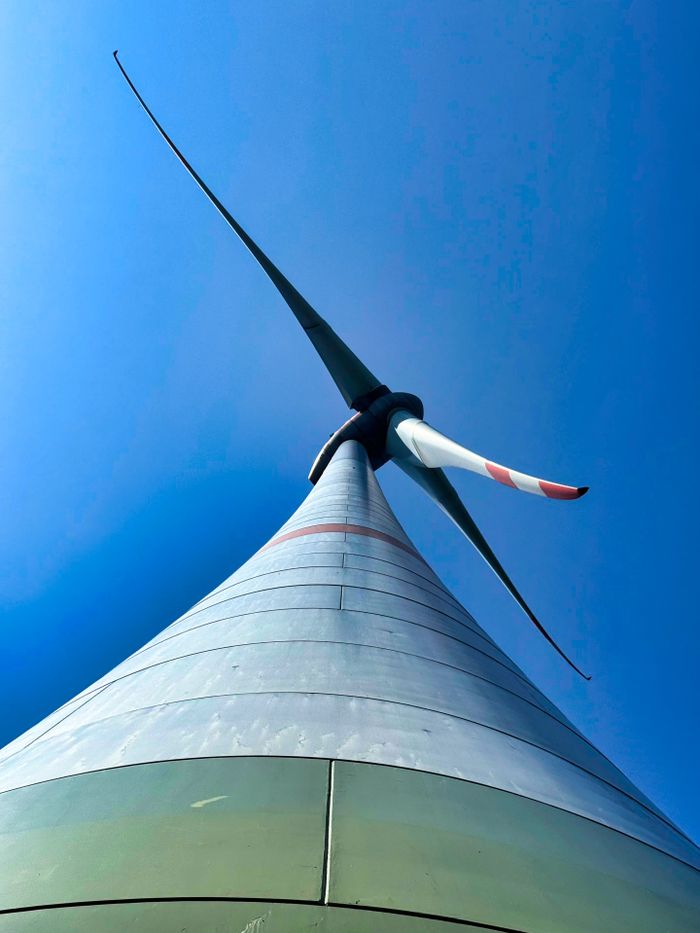 Striking low-angle view of a wind turbine with a clear blue sky background, showcasing renewable energy.